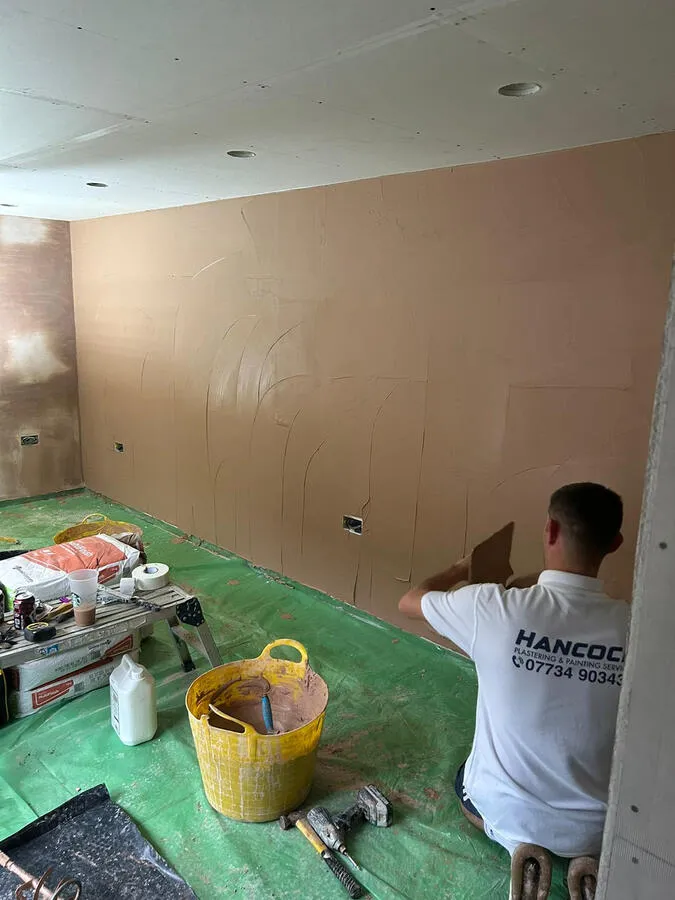 Plasterer applying skim coat to wall
